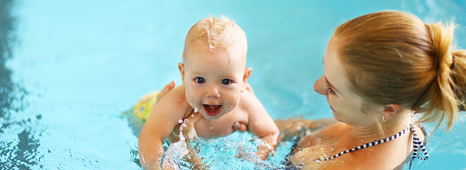 adult female with a baby in a pool swimming 